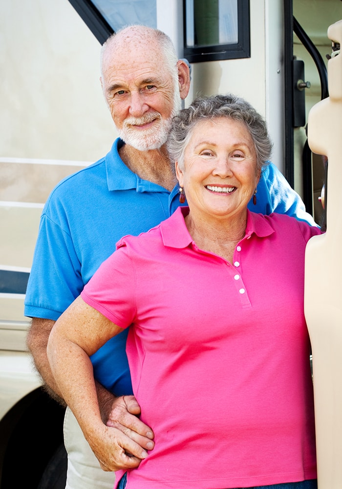 smiling couple in front of an rv